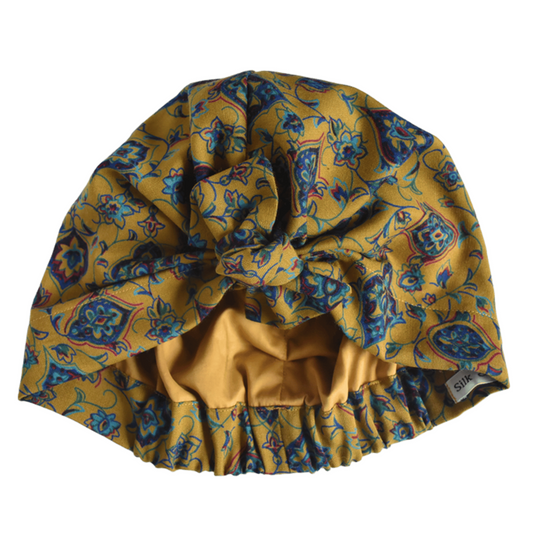 A mustard yellow vintage liberty fabric hair turban with a blue and purple floral pattern, featuring a elasticised ruffled bottom, silk or cotton lined
