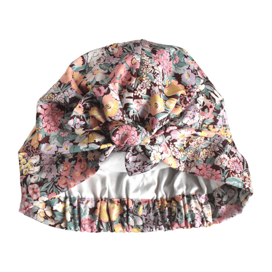 Liberty Cottage Garden floral print turban or sleep bonnet with a large bow on top and a elasticated back, shown against a plain white background.