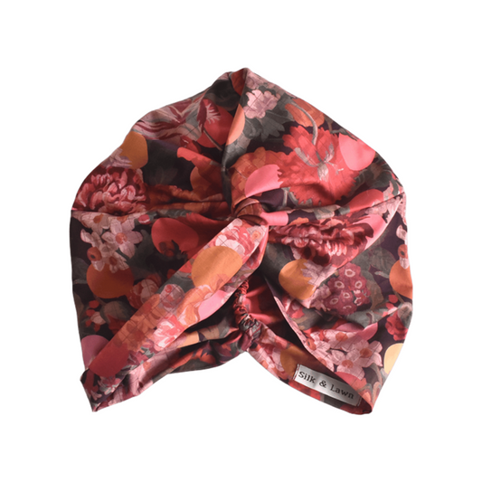 The reverse or back side of a knotted turban-style headscarf with a vibrant floral print in shades of red, pink, orange, and dark brown, featuring Liberty Myrtle & Mary Tana Lawn Cotton by hair accessories brand Silk & Lawn