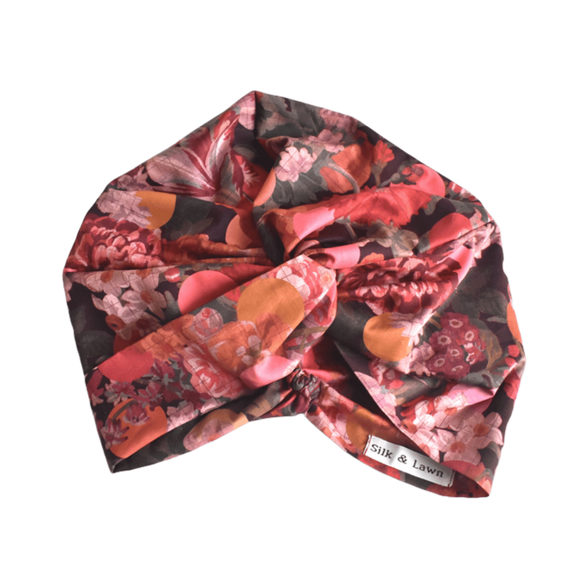 A knotted turban-style headscarf with a vibrant floral print in shades of red, pink, orange, and dark brown, featuring Liberty Myrtle & Mary Tana Lawn Cotton