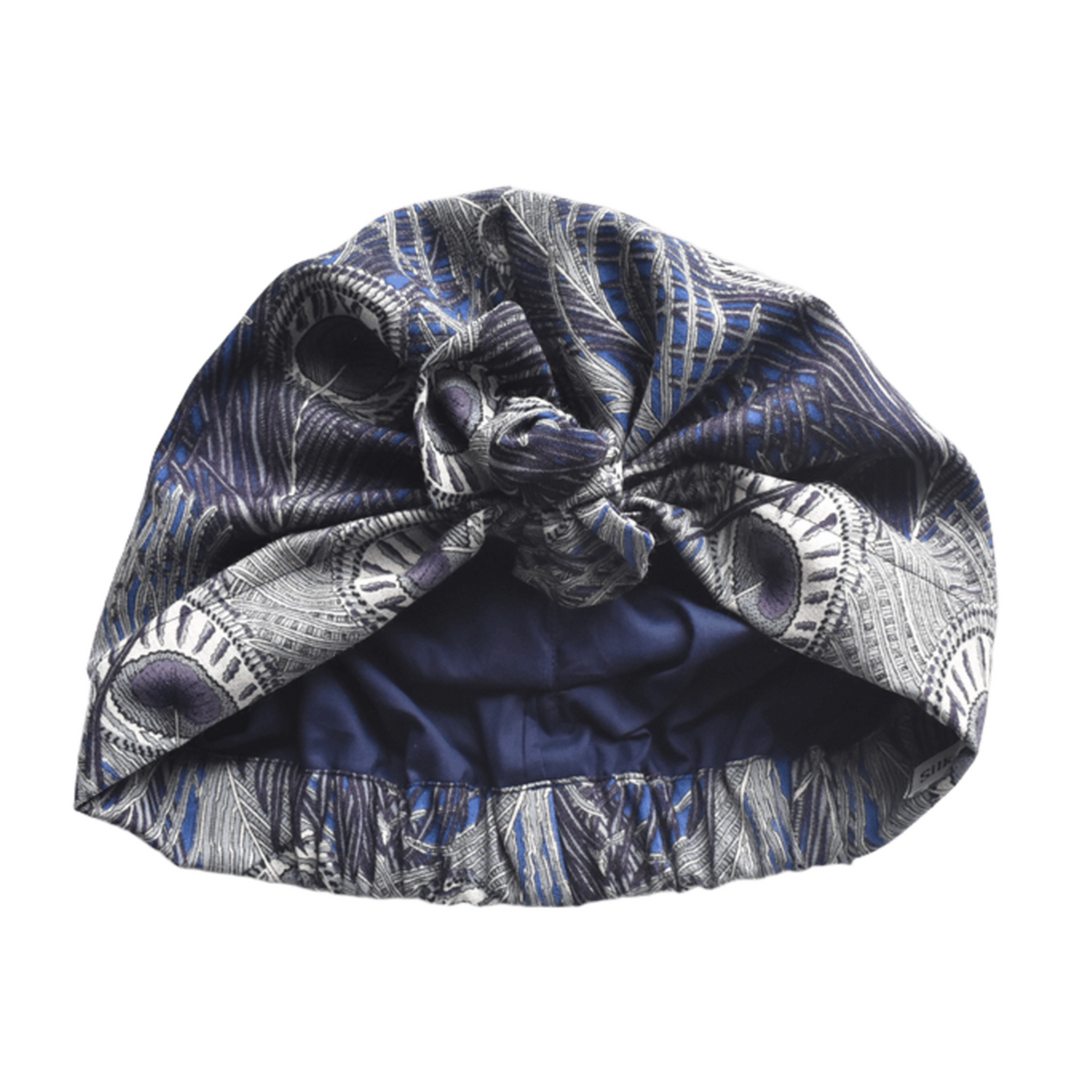 A knotted fabric headwrap or turban-style hair accessory in Vintage Liberty Hera Feather in Lapis blue   - Varuna Wool / peacock feather blue, gray, and white pattern, shown on a plain white background.