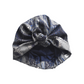 A knotted fabric headwrap or turban-style hair accessory in Vintage Liberty Hera Feather in Lapis blue   - Varuna Wool / peacock feather blue, gray, and white pattern, shown on a plain white background.